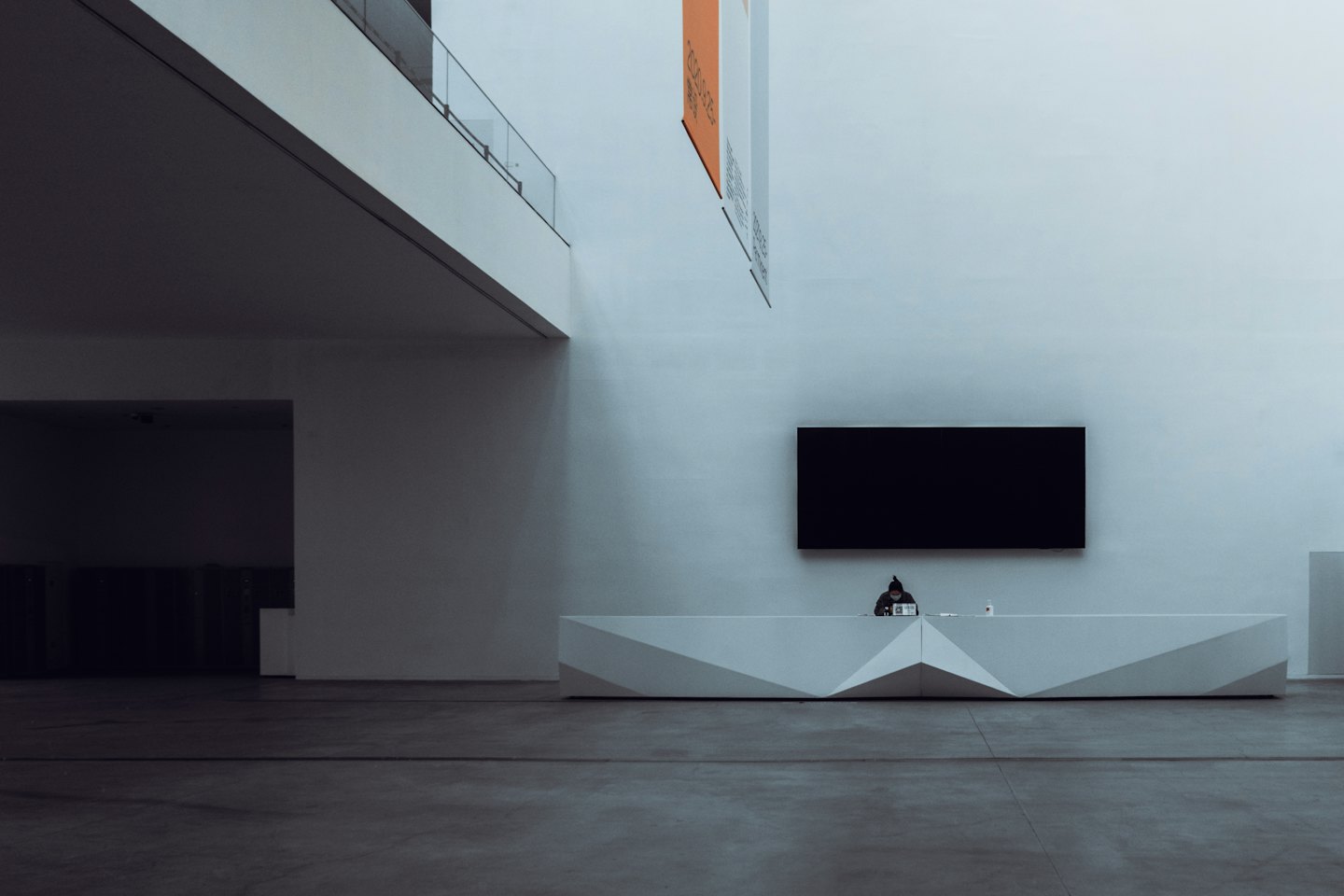 Receptionist sits at a modern desk in a corporate lobby.